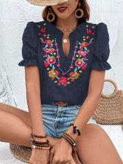 Navy blue embroidered puff sleeve blouse with floral neckline detail and textured fabric.