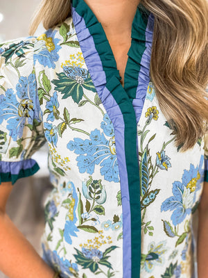 Floral frilled blouse with blue, green, and yellow flowers, featuring striped trim and ruffled cuffs.