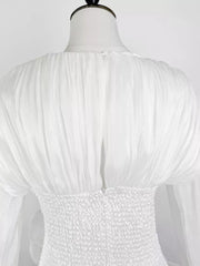 White cotton mini dress with ruched bodice and voluminous ruffled sleeves.