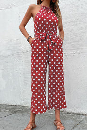 Red polka dot halter neck palazzo jumpsuit with belted waist and pockets.