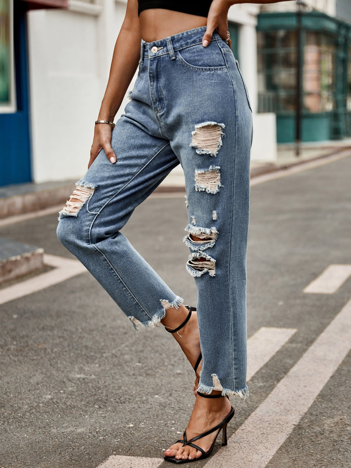 Medium wash denim jeans with ripped knees and raw hem straight leg cut.