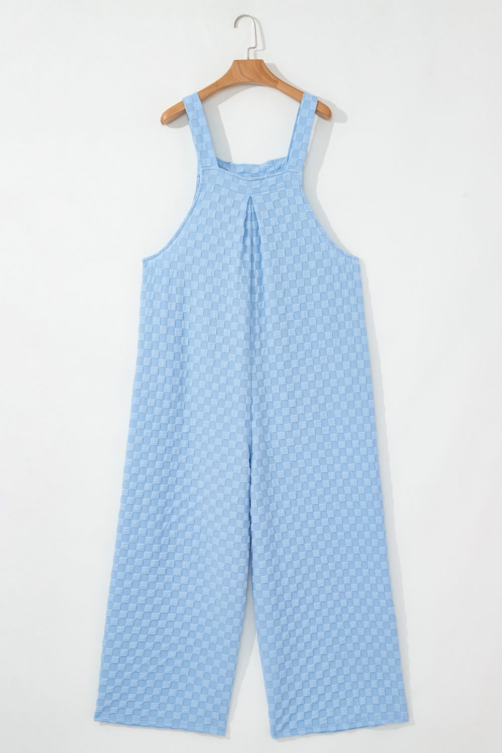 Light blue checkered textured palazzo jumpsuit with button straps and wide legs.