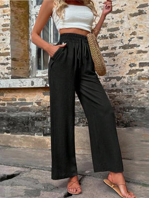 Black linen palazzo trousers with drawstring waist and pockets, styled casually.