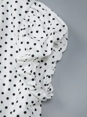 White t-shirt with black polka dots and ruched sleeve detail.