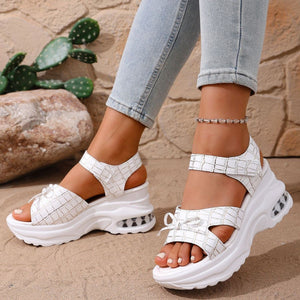 White textured open-toe wedge sandals with adjustable straps and bow detail.