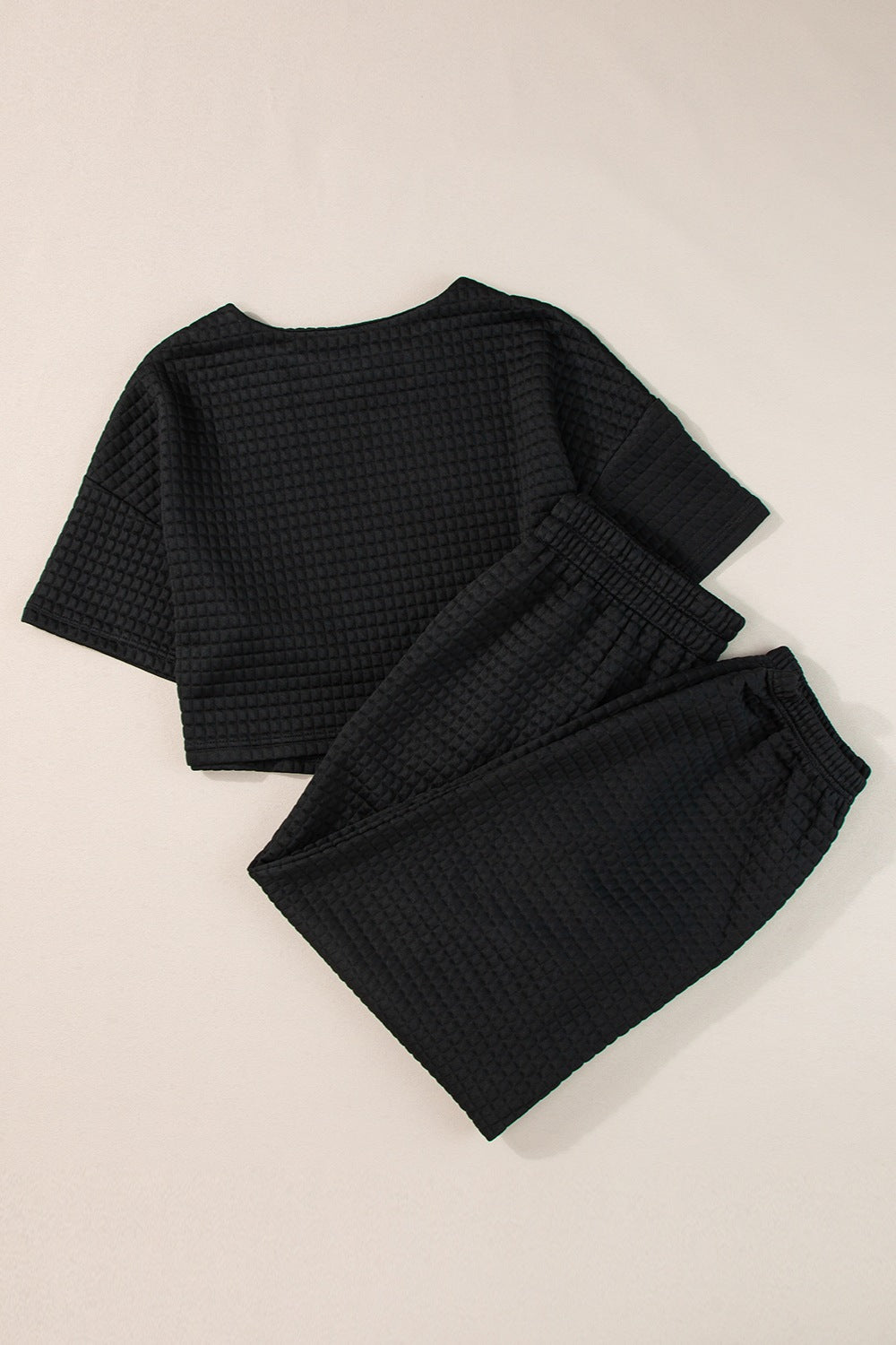 Black quilted knit crop top and jogger set with crewneck and elastic waistband.