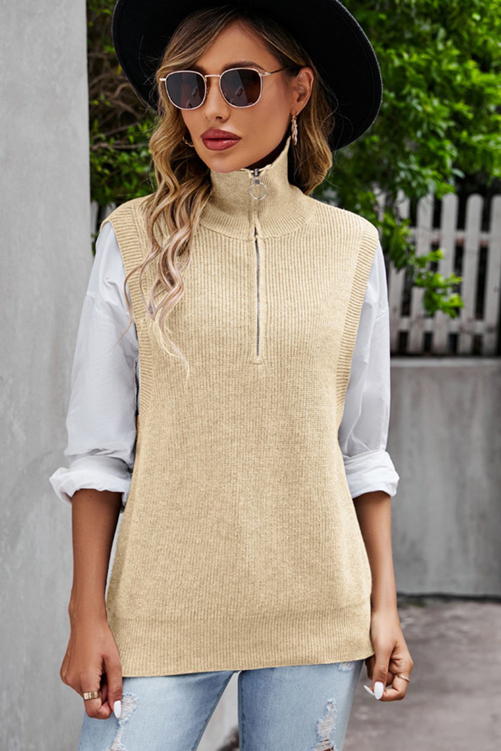 Tan ribbed knit vest with a mock neck and quarter zip, styled over a white shirt.