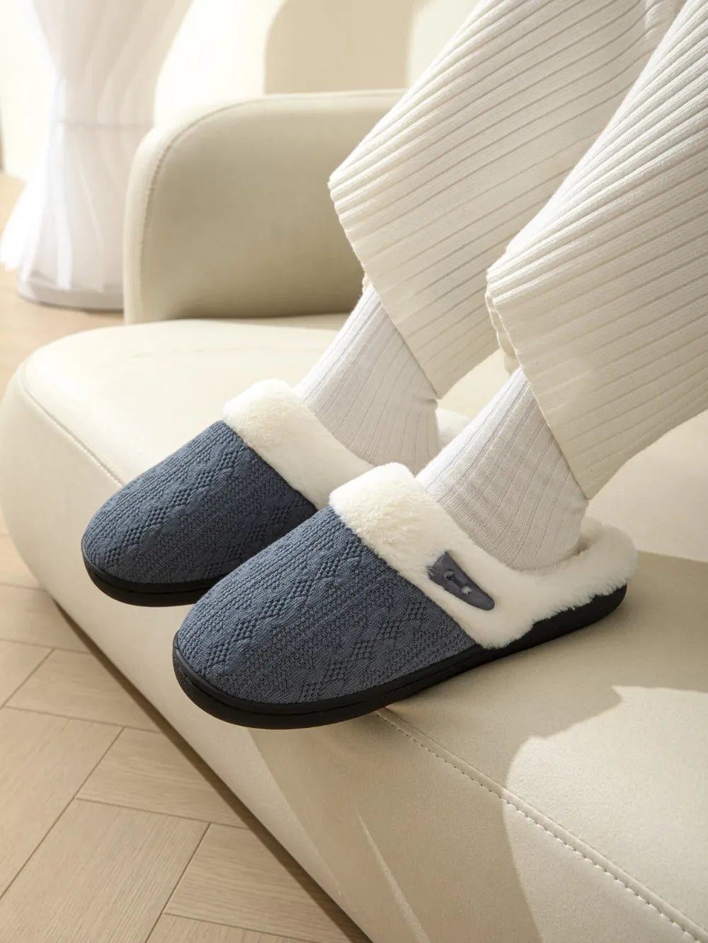 Dusty blue cable knit shearling house slippers with faux fur trim and button detail.