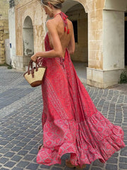 Backless maxi dress with deep rose paisley print, halter neck with tassels, and tiered ruffled hem.