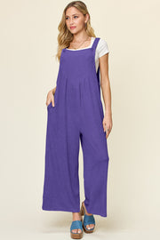 Ribbed wide-leg pinafore jumpsuit in purple with button straps and pockets.