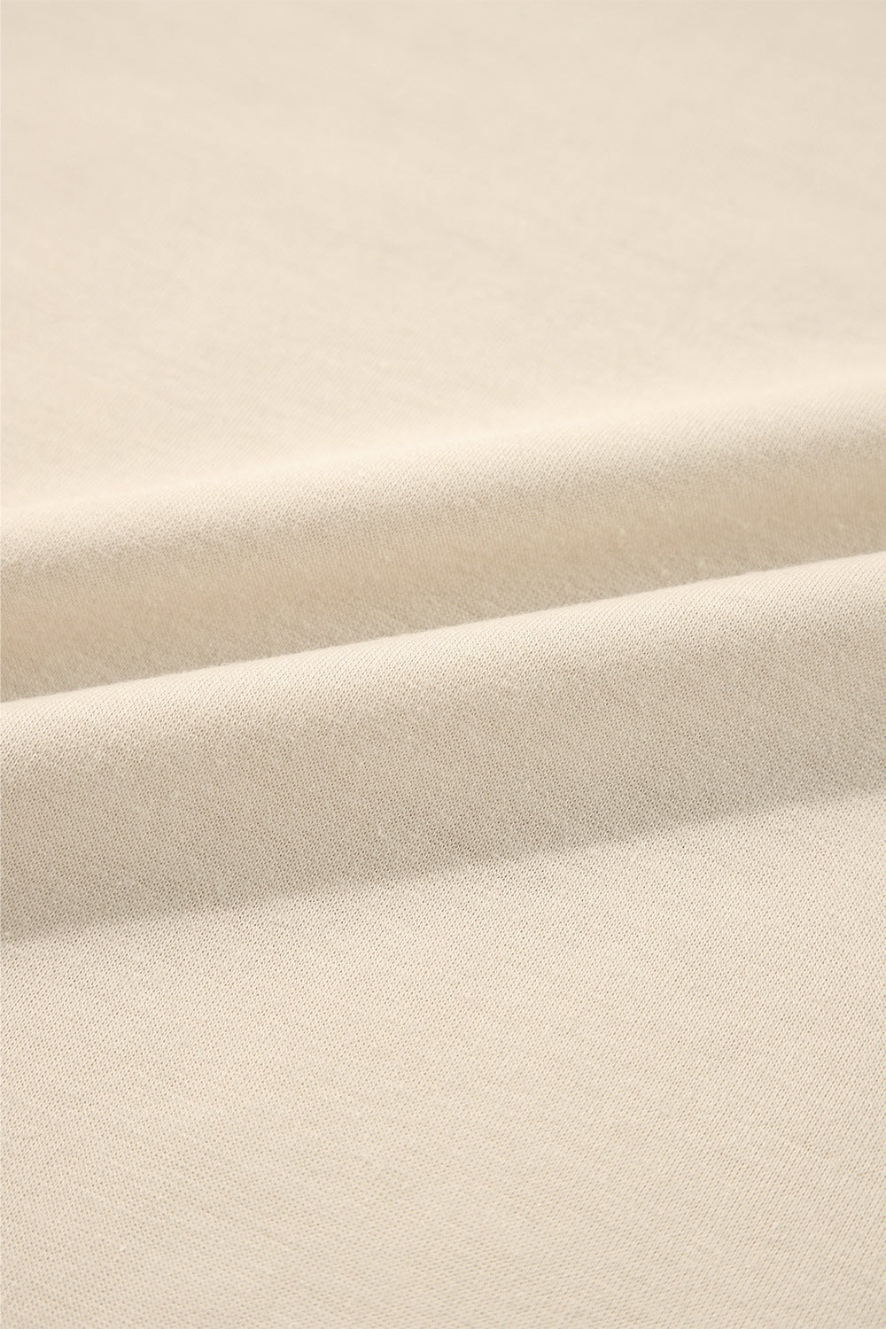 Cream sweatshirt fabric detail showing soft texture and subtle ribbing.