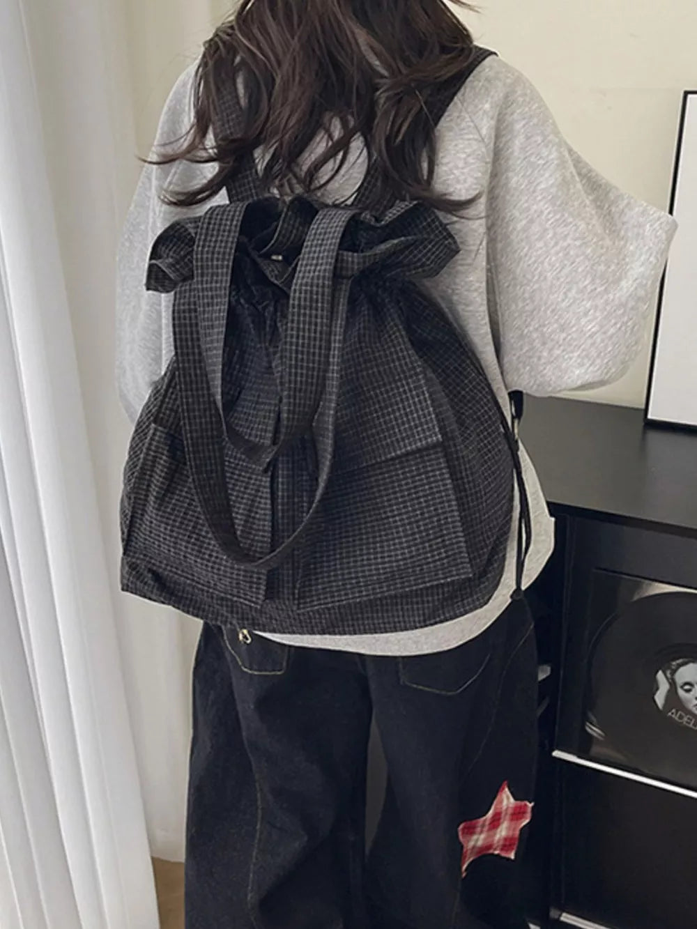 Chic grey plaid drawstring backpack with front pockets and adjustable straps.