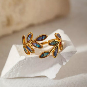 Gold bypass ring with leaf design and iridescent blue accents.