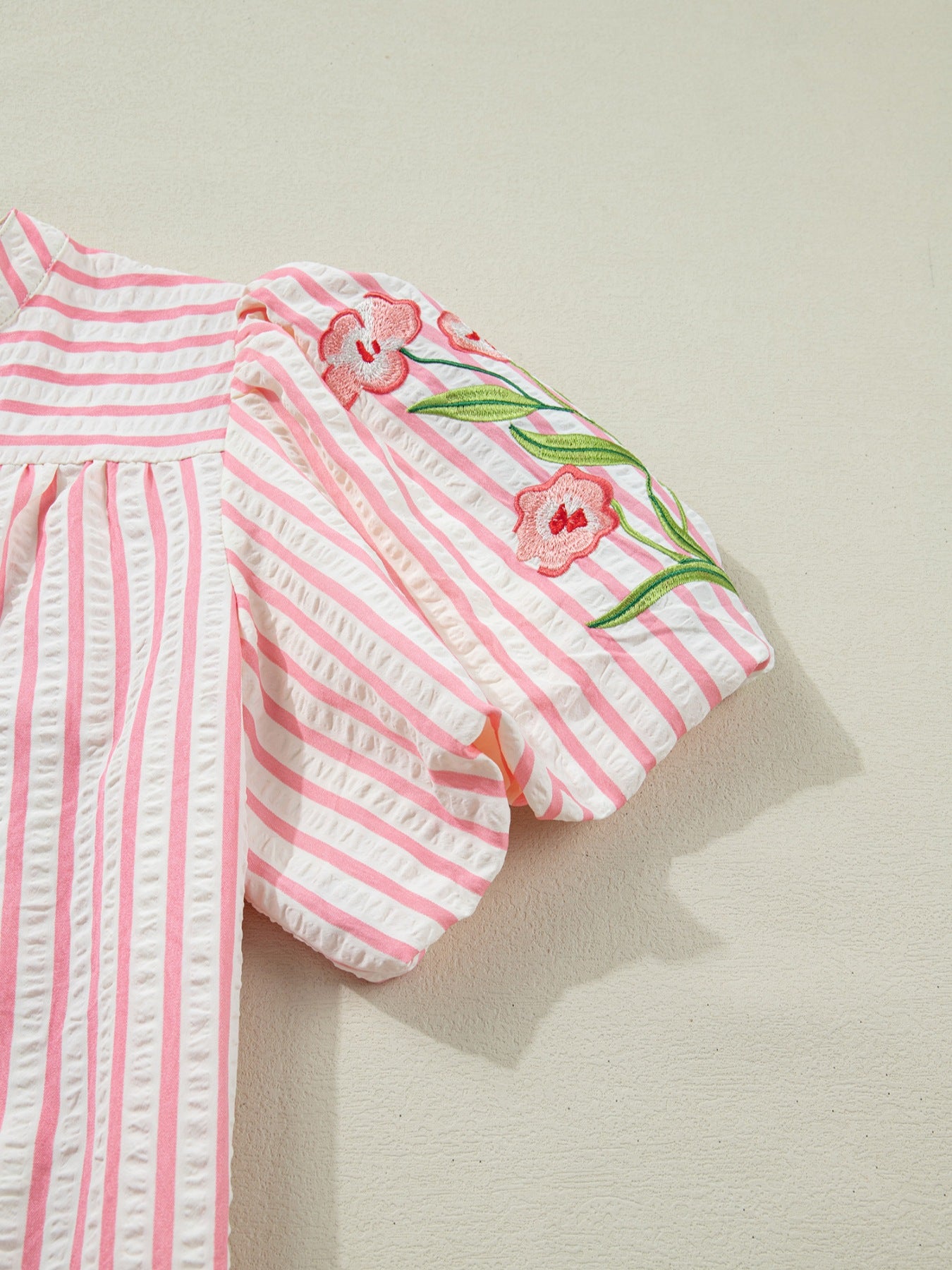 Pink and white striped blouse with floral embroidery on puff sleeves.