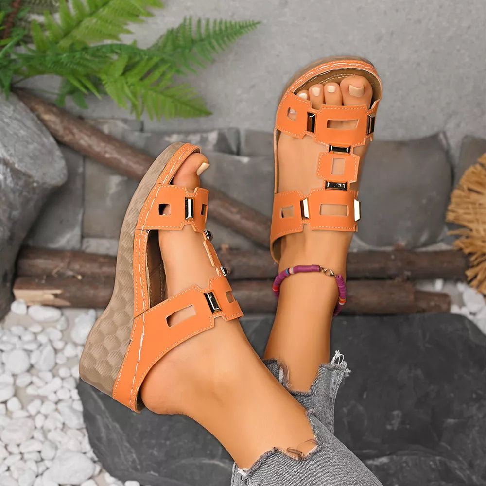 Orange open-toe wedge sandals with cutouts and gold accents.