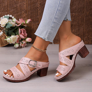 Pink laser-cut criss-cross block heel sandals with buckle detail.