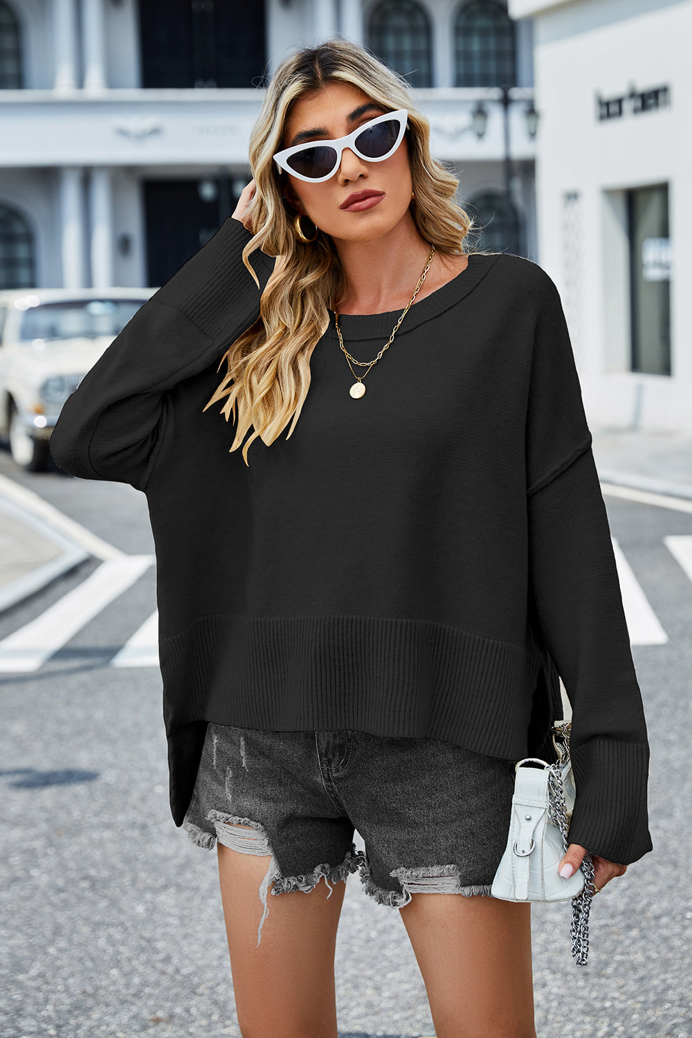 Black acrylic knit sweater with flared sleeves and split hem detail.