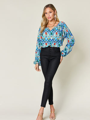 Prismatic ikat blouse with voluminous sleeves in blue and green, V-neck, long balloon sleeves.