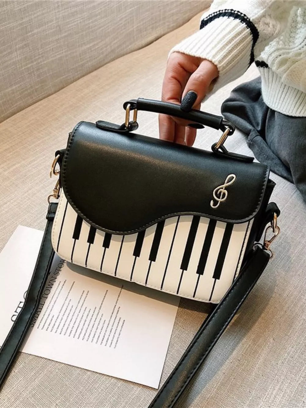 Black and white piano key crossbody bag with treble clef detail and top handle.