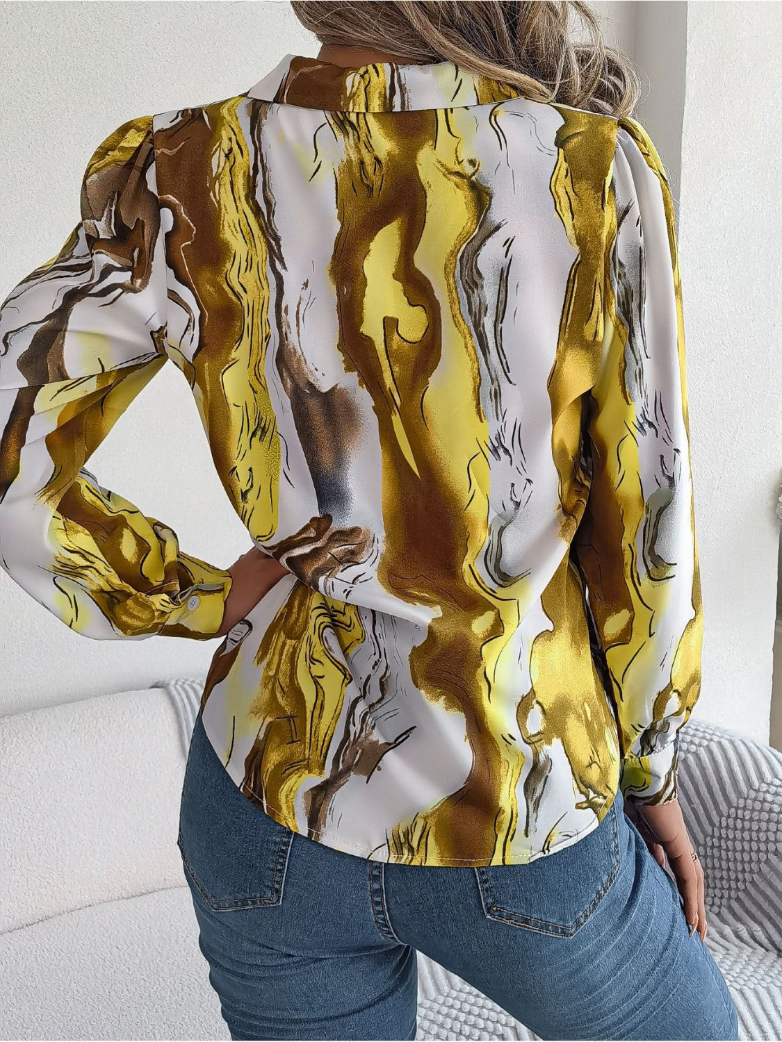 Women's abstract swirl print silk blouse in yellow and white with button cuffs.
