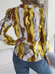 Women's abstract swirl print silk blouse in yellow and white with button cuffs.