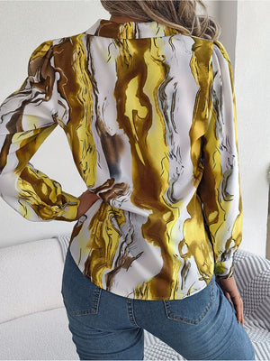 Women's abstract swirl print silk blouse in yellow and white with button cuffs.