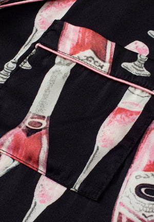 Black silk pajama set with champagne print and pink piping detail.