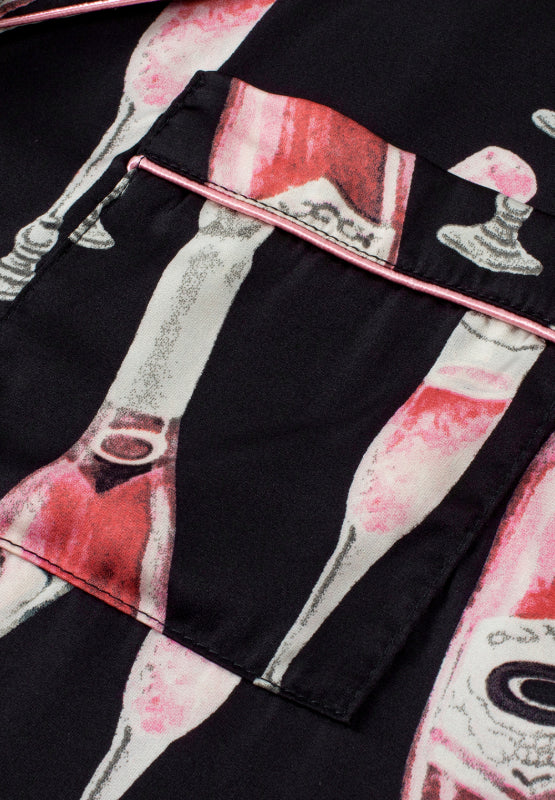 Black silk pajama set with champagne print and pink piping detail.
