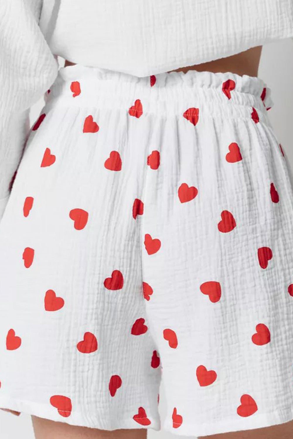 White gauze pajama shorts with a red heart print and elastic waistband.