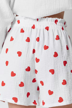 White gauze pajama shorts with a red heart print and elastic waistband.
