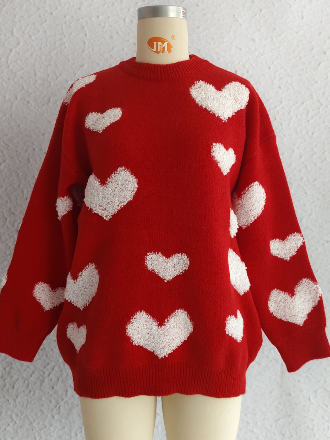 Red acrylic knit sweater with textured white heart appliqués, crewneck, long sleeves.