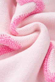 Pink knit sweater with heart appliqué and balloon sleeves.