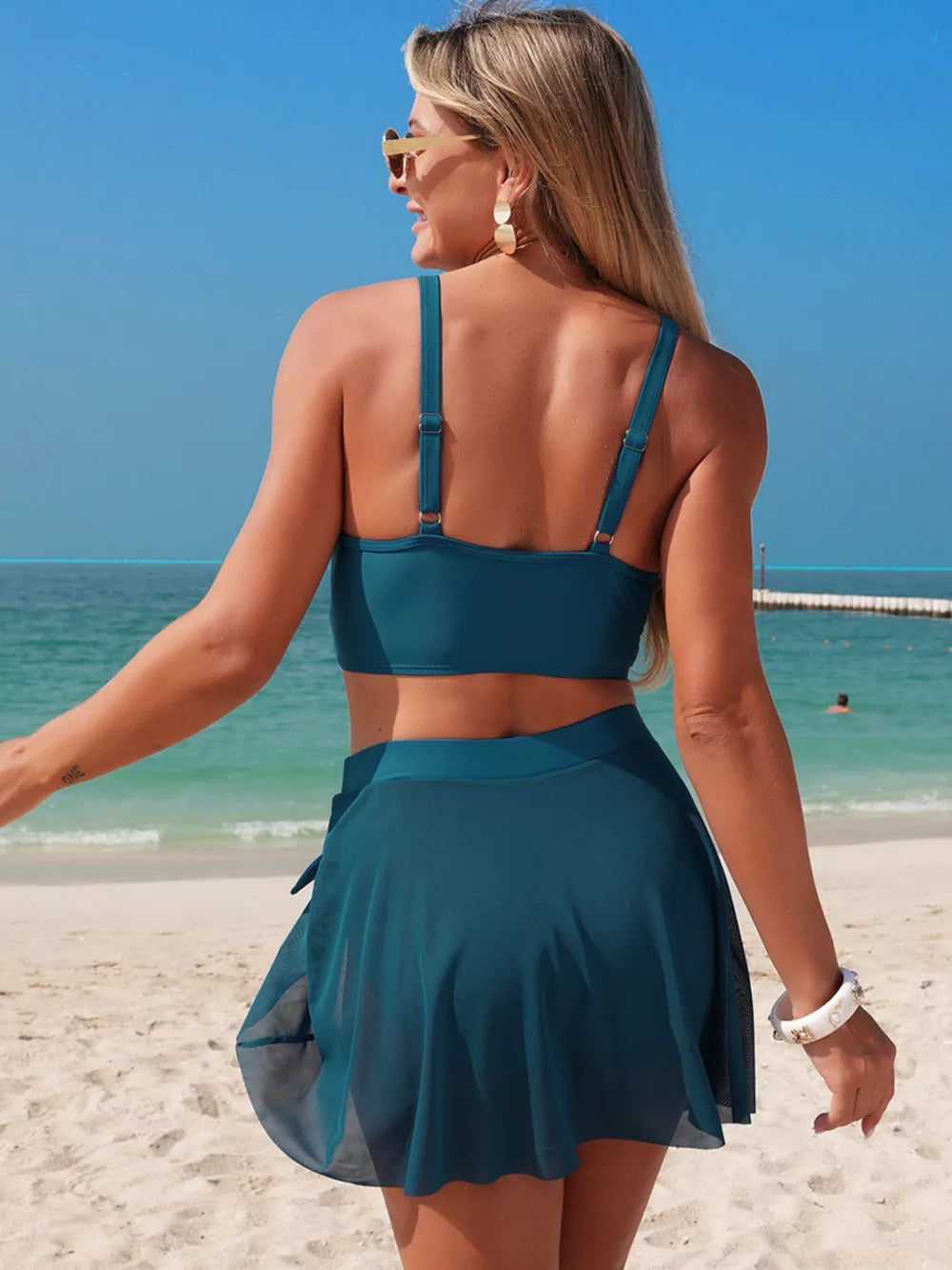 Peacock blue bikini set with high-waist skirt and adjustable straps.
