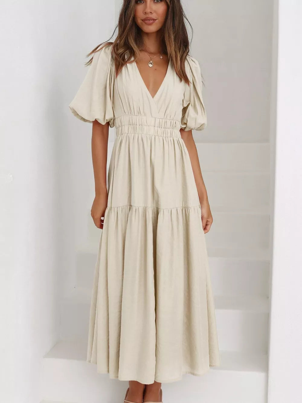 Cream midi dress with V-neck, cinched waist, tiered skirt, and puff sleeves.