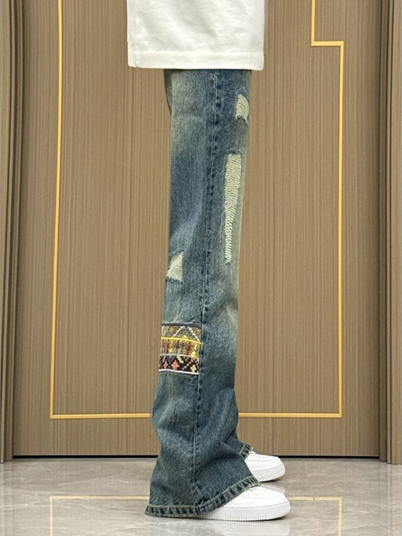 Distressed blue wash wide-leg jeans with patchwork details and ripped accents.