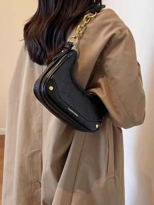 Black crescent shoulder bag with chunky gold chain and embossed text.