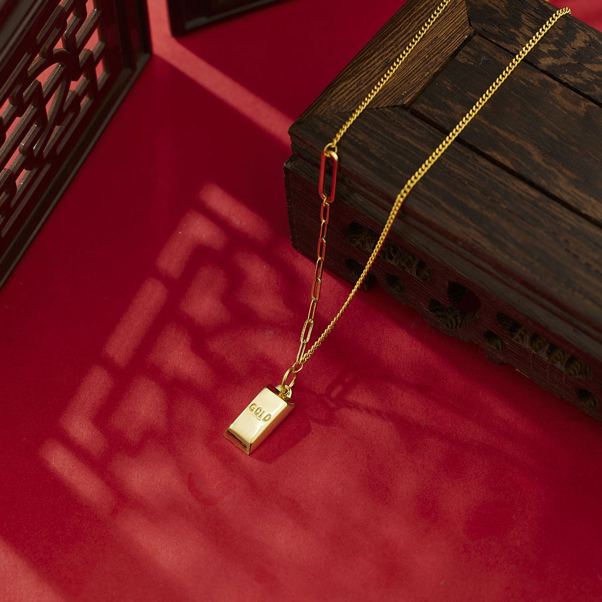 Gold-plated bar pendant necklace with curb links and a paperclip chain detail.