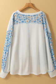 White waffle knit blouse with blue floral print sleeves and neckline detail