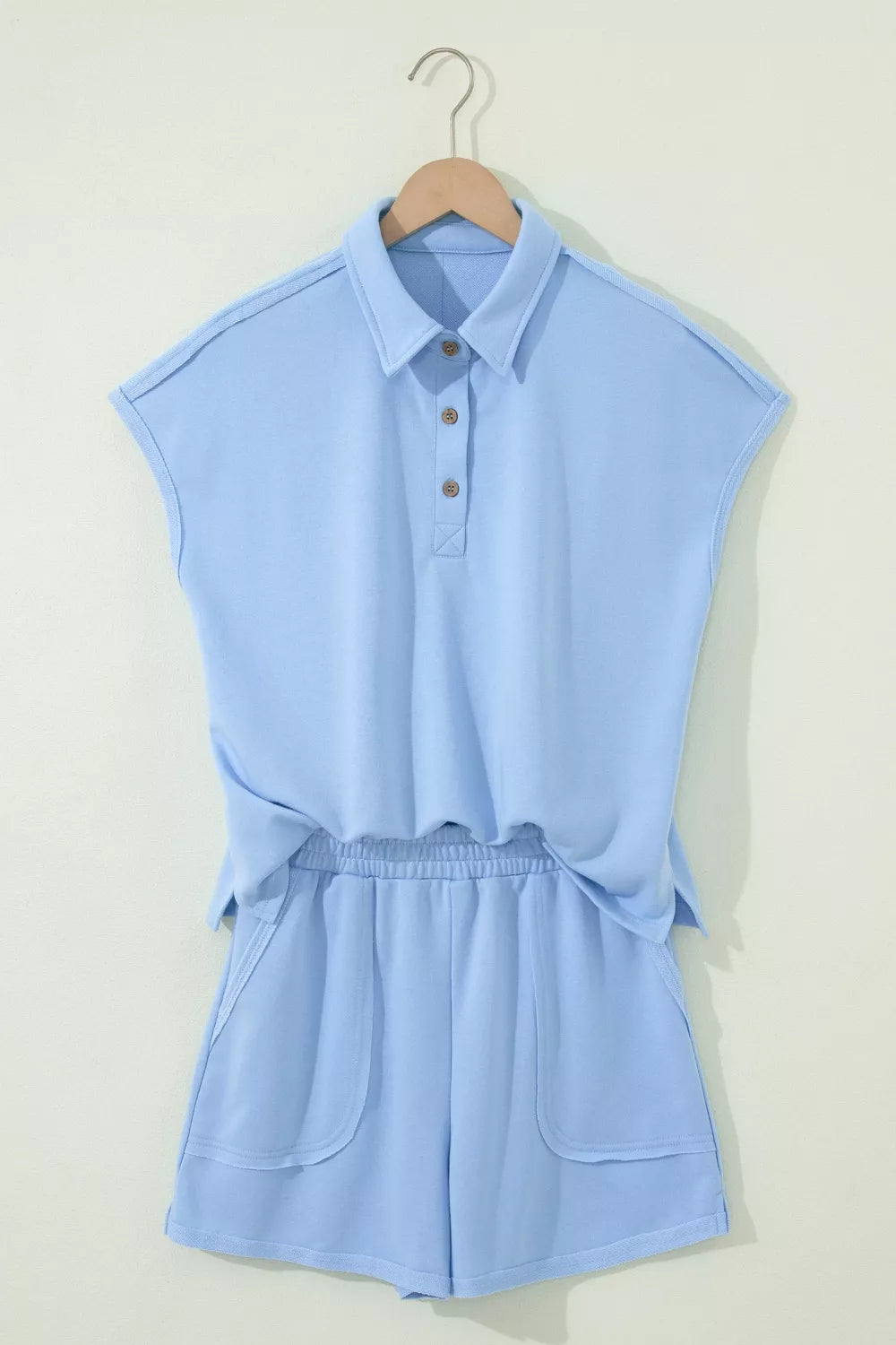 Light blue sleeveless polo shirt and shorts set with button detail and pockets.