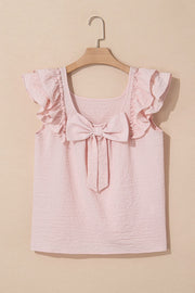 Blush pink textured blouse with ruffle sleeves and a large front bow detail.