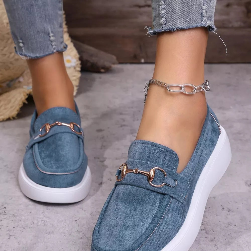 Blue suede loafers with gold horse-bit detail and white soles.