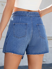 Medium wash denim skort with asymmetric wrap, raw hem, and back pockets.
