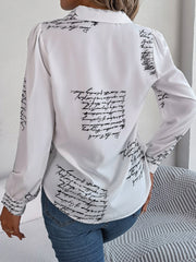 White collared blouse with black script print and puff sleeves.