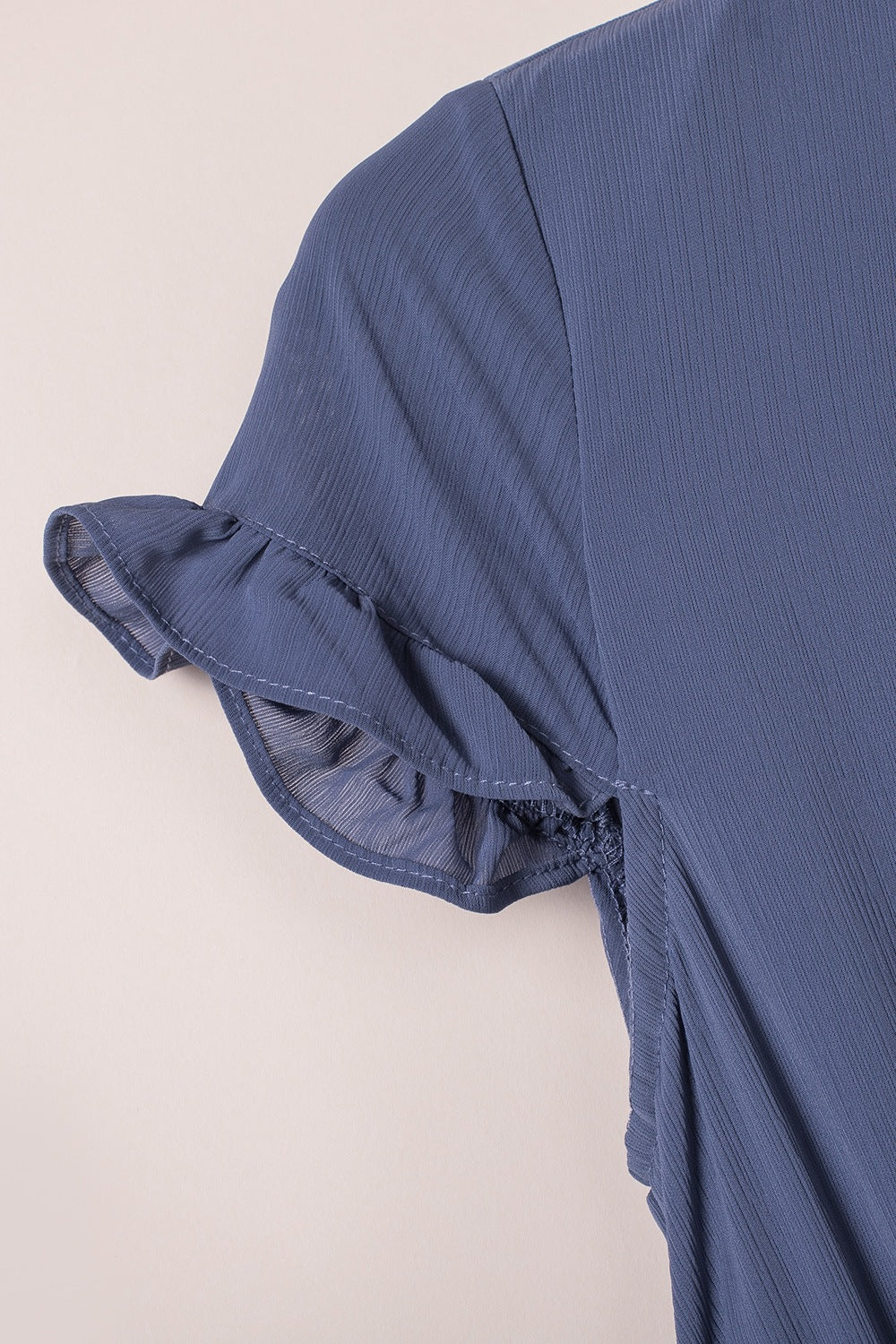 Dusty blue mini dress with ruffled short sleeves and V-neck detail.
