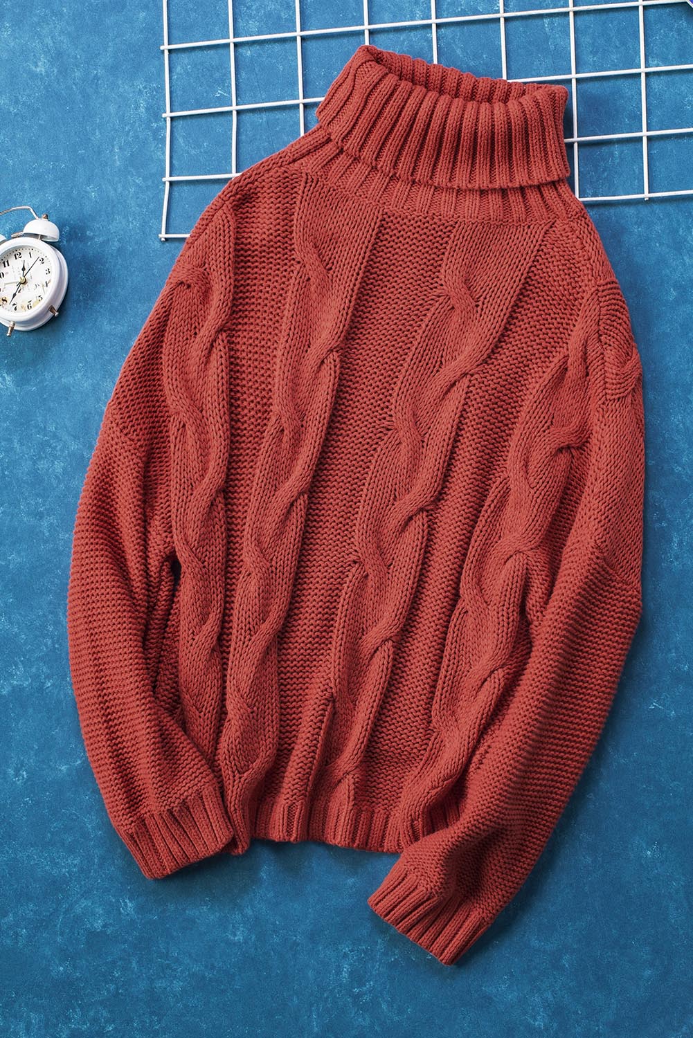 Rust cable knit turtleneck sweater with relaxed fit and ribbed cuffs.