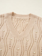 Beige V-neck knit sweater with pearl details and open knit pattern.