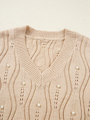 Beige V-neck knit sweater with pearl details and open knit pattern.