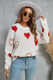 White knit crewneck sweater with allover red and blush pink heart motif.