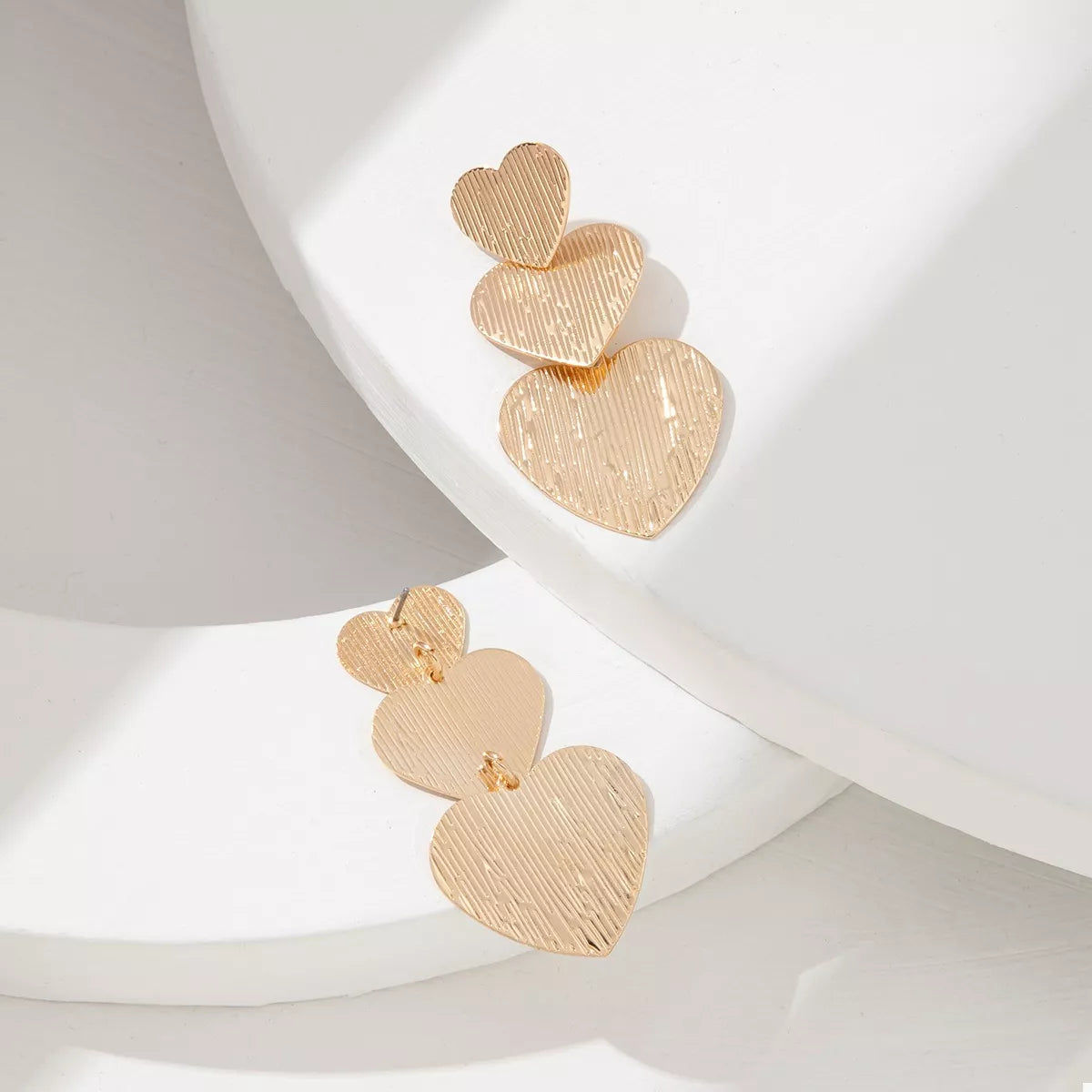 Gold heart-shaped dangle earrings with textured finish
