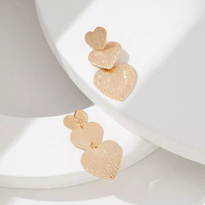 Gold heart-shaped dangle earrings with textured finish